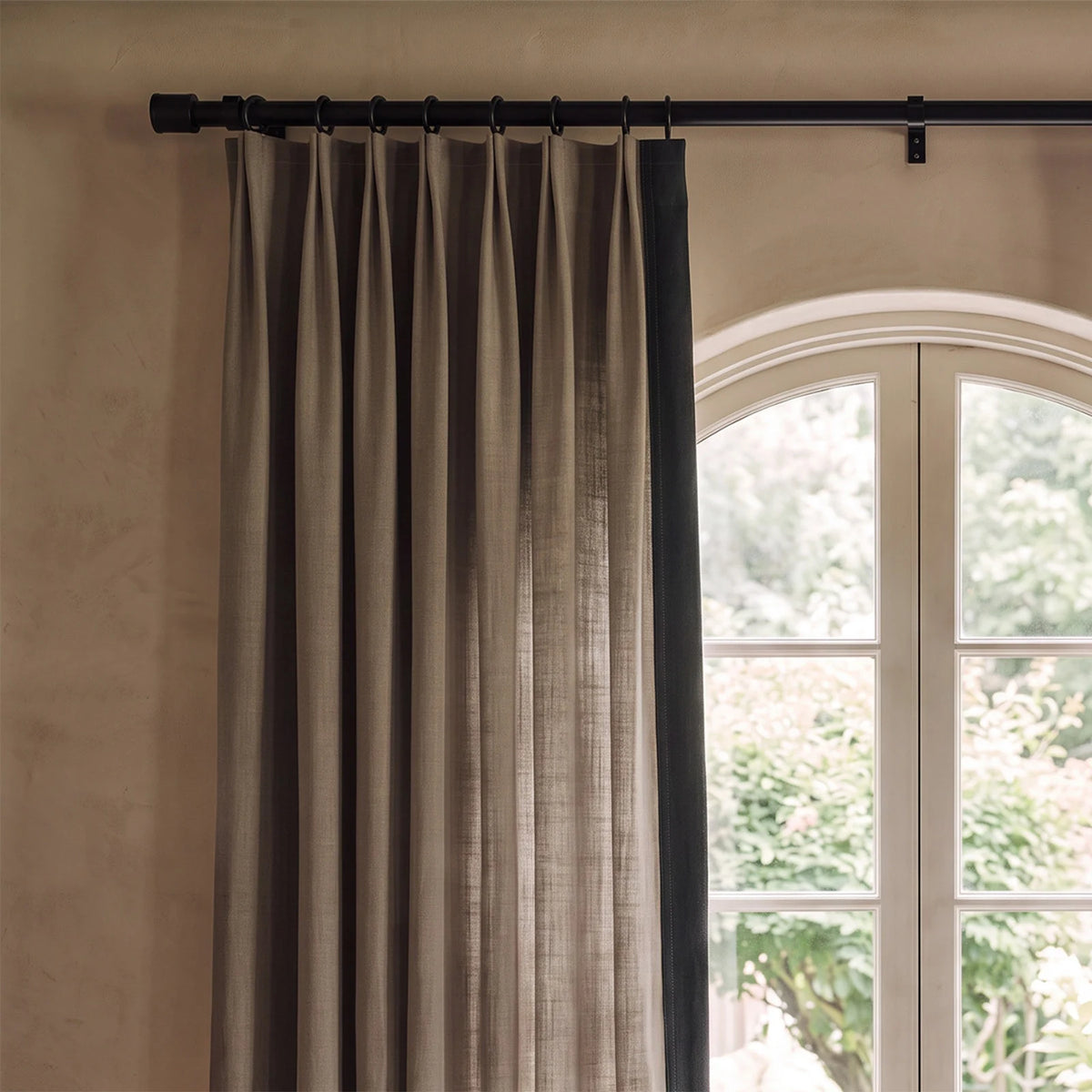 Close-up of two-tone tailored pleat curtains showing the contrasting leading-edge border and fabric texture.