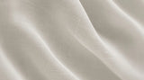 Close-up of ivory curtain fabric with soft folds and a smooth woven surface.
