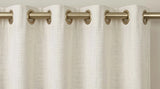 Ivory grommet curtain header installed on a brass curtain rod.