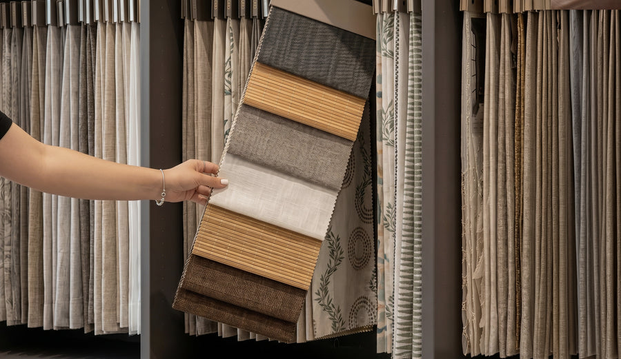 Hand selecting neutral fabric samples from a curtain showroom display.