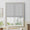Light gray woven fabric flat Roman shade partially lowered over a white framed window