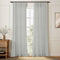 Natural Aria pinch pleat curtains installed around a tall window in a neutral room.