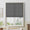 Charcoal woven flat Roman shade partially lowered over a white framed window in a bright living room