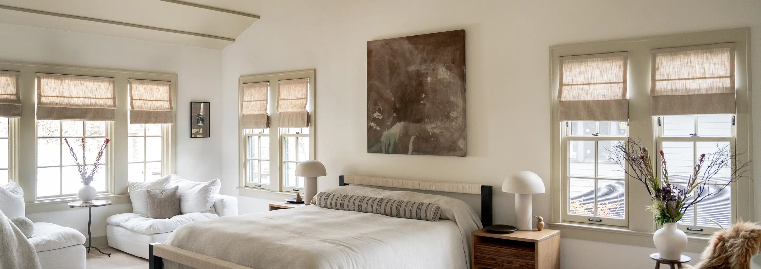 Modern bedroom with large bed, windows, and decorative elements.
